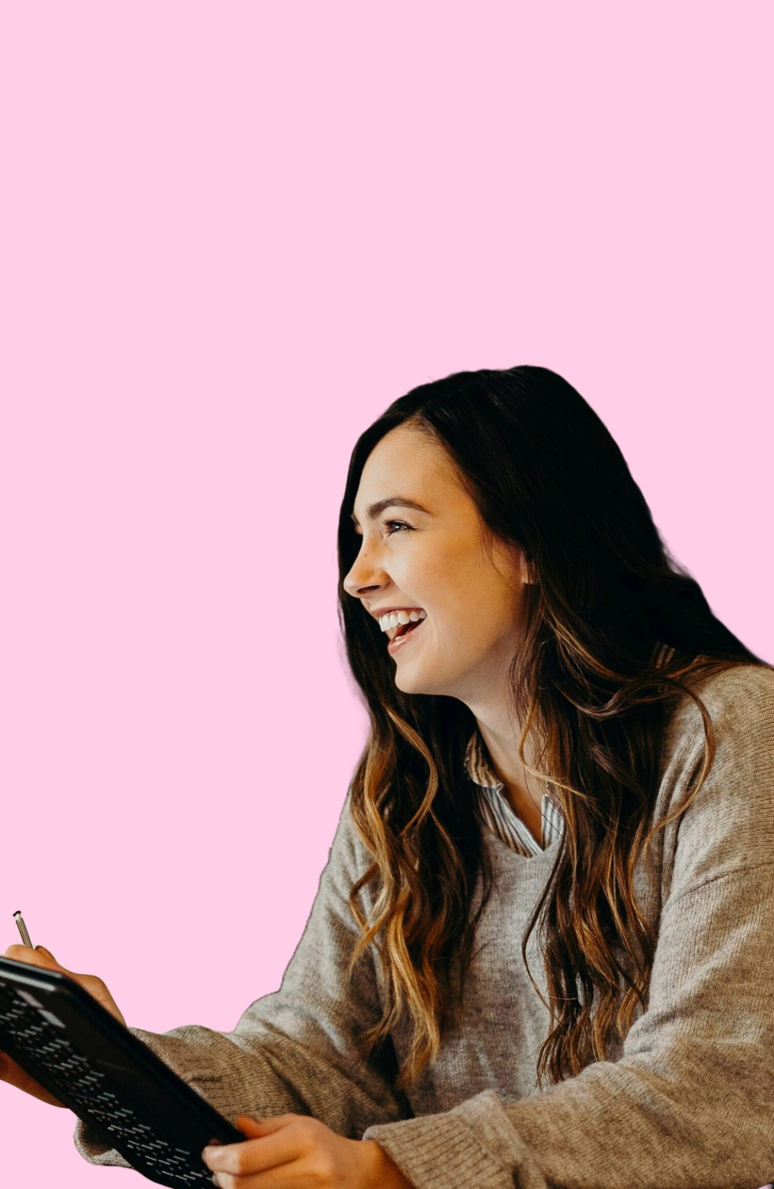 A woman smiling while holding a tablet, set against a pink background.