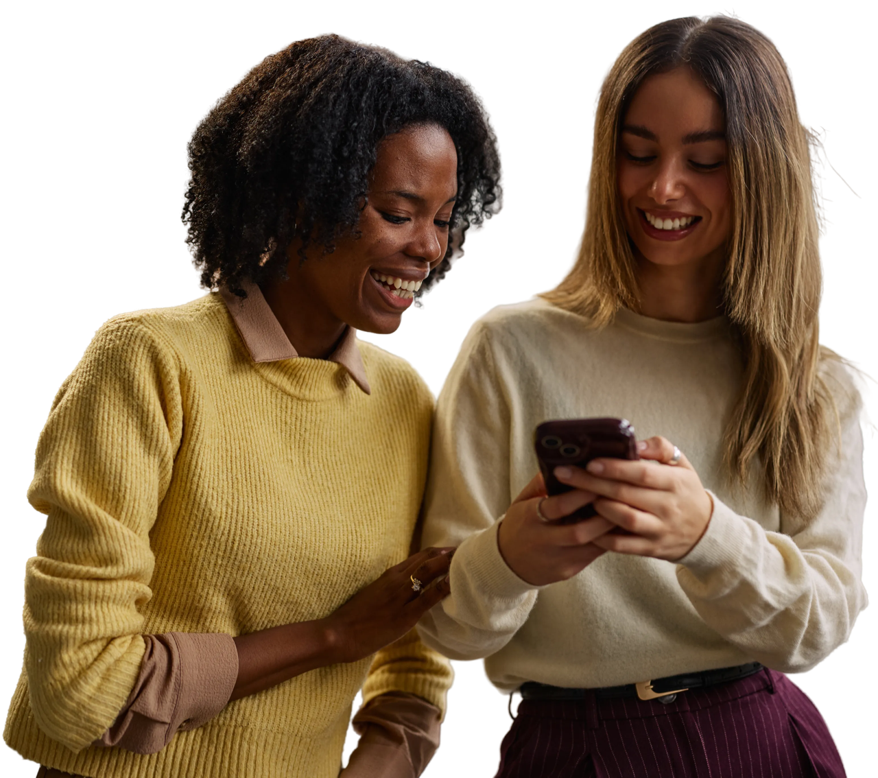 Two women smiling as they look at a phone together