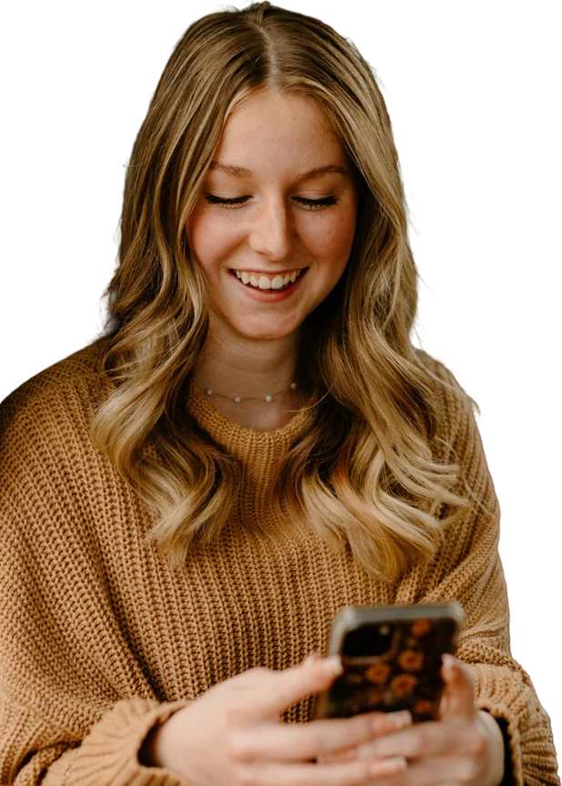 Woman in a knitted jumper smiling at her phone