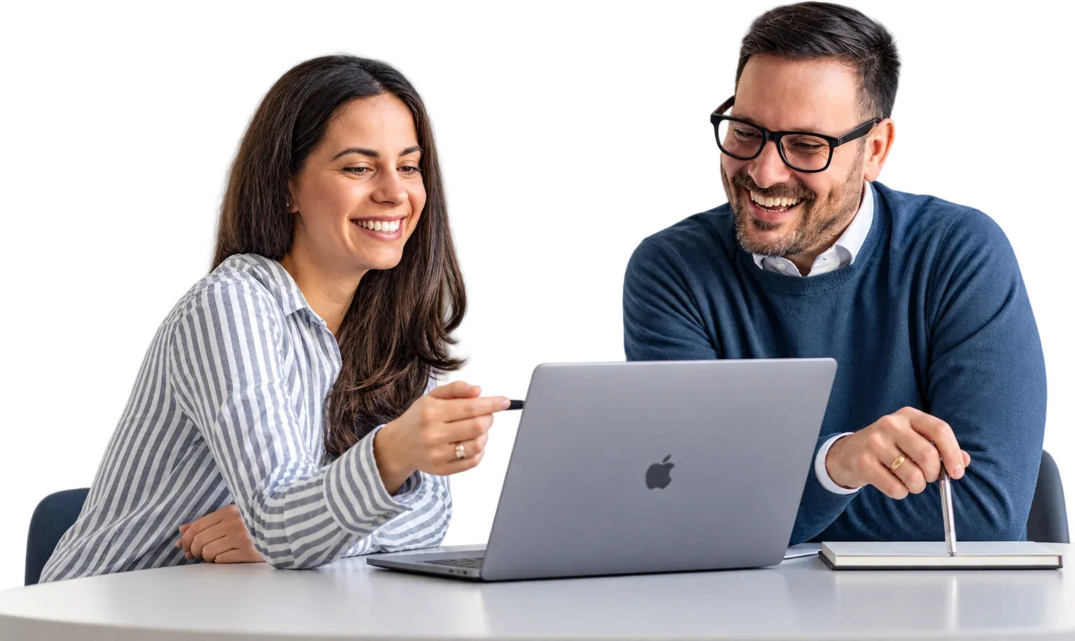 A woman and a man smiling as they look at a laptop together at a desk